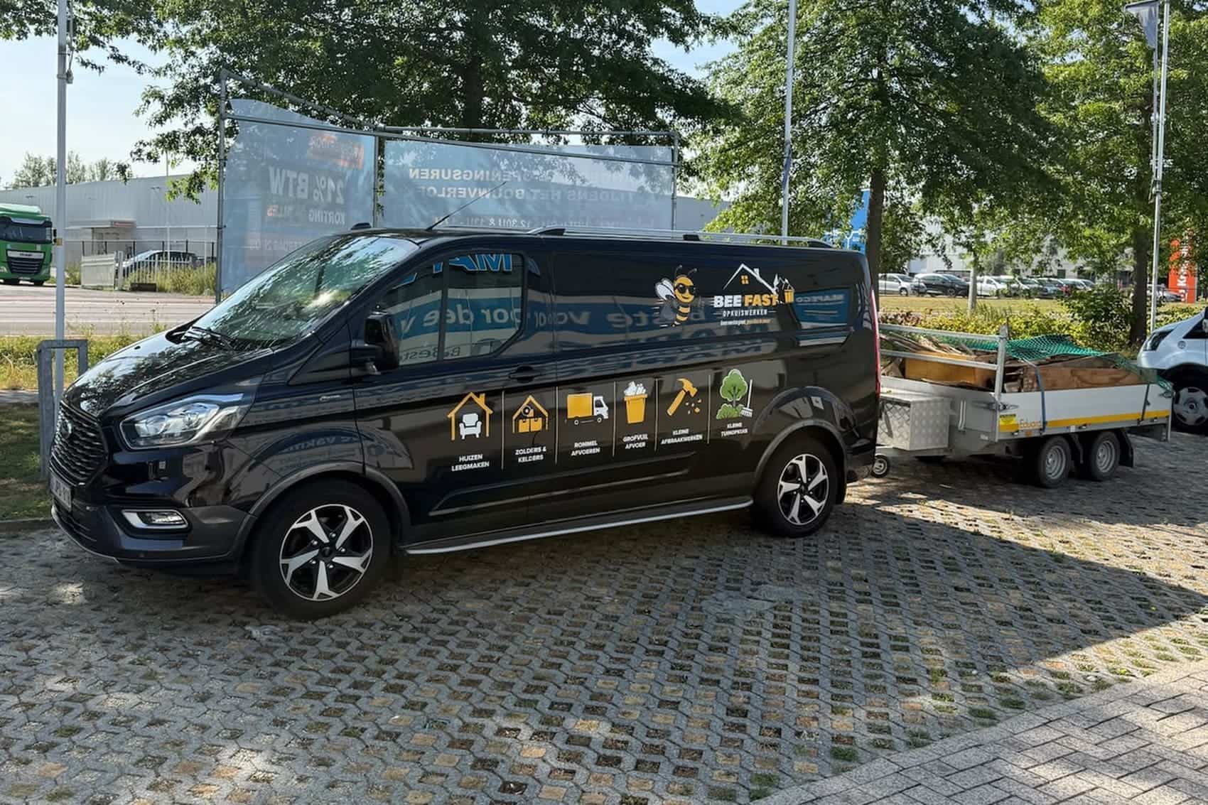 De bestelwagen van Bee Fast met een volgeladen aanhangwagen, klaar om het afval af te voeren