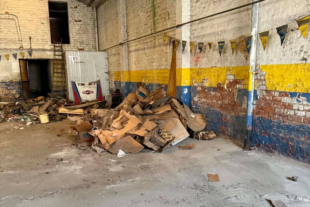 Hoop hout, karton en bouwafval tegen de muur van een loods voor de opruiming