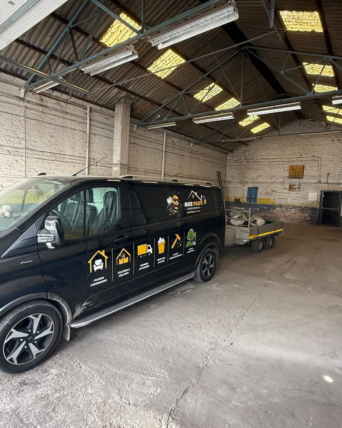 De bestelwagen van Bee Fast met aanhangwagen in de leeggemaakte loods, vloer geveegd